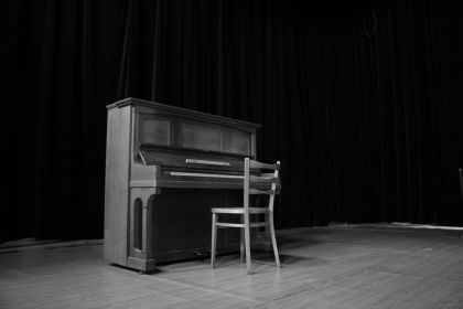 Lone piano sits in dark room. 